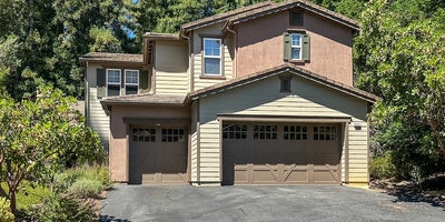 Tan home with one double and one single garage door